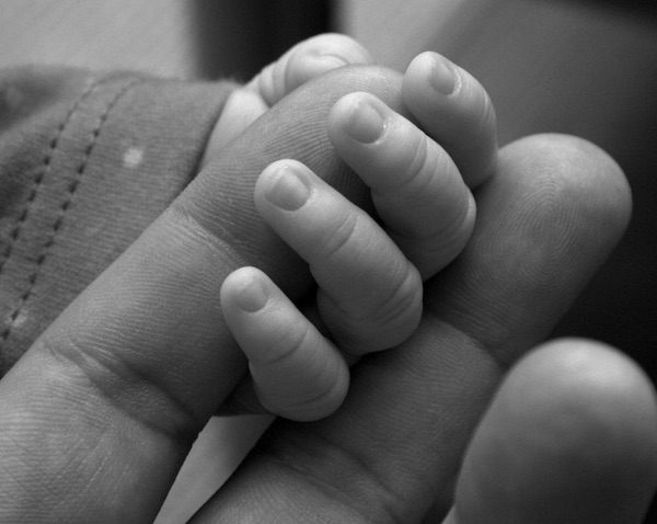 mano de bebé cogiendo dedos de su padre