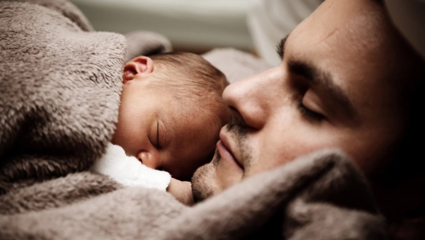 Papá primerizo durmiendo con bebé
